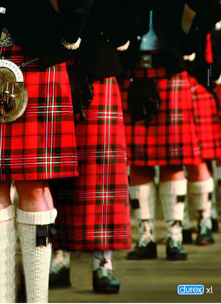 Publicité Durex XL : une rangée d’hommes vus de dos en kilts écossais à tartan rouge, dont l’un est nettement soulevé sur le devant