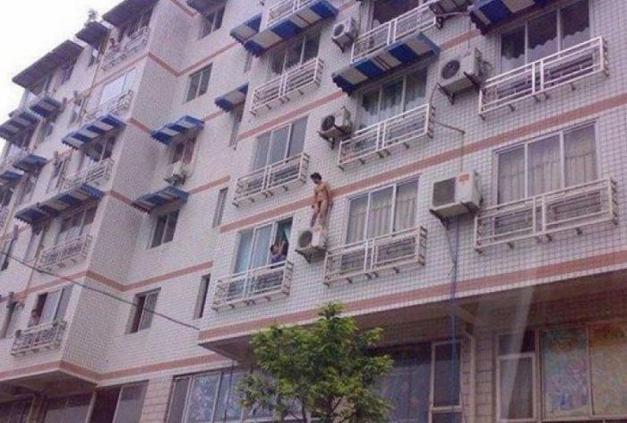 Façade d'immeuble résidentiel avec climatiseurs et habitant au balcon